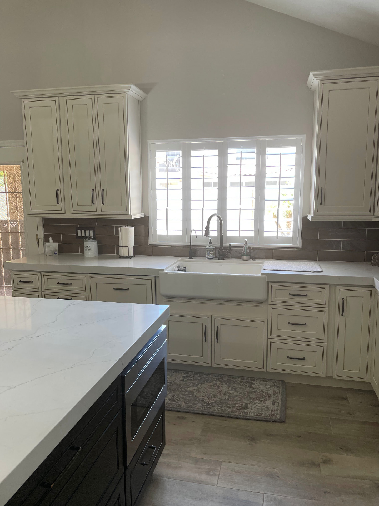 Farmhouse apron sink set in ivory cabinetry with quartz counters